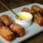 Bolinho de carne seca crocante servido em prato