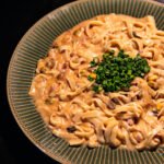 Prato de macarrão fettuccine cremoso ao molho rosado com bacon e cebolinha picada no topo
