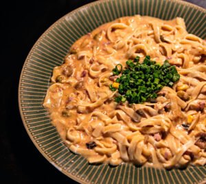 Prato de macarrão fettuccine cremoso ao molho rosado com bacon e cebolinha picada no topo
