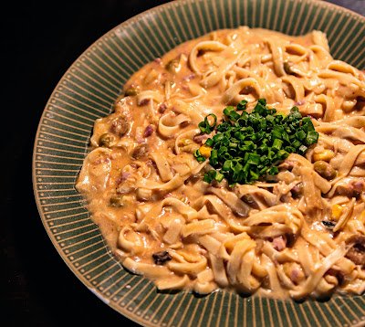 Prato de macarrão fettuccine cremoso ao molho rosado com bacon e cebolinha picada no topo
