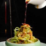 Espaguete de abobrinha em tiras finas servido com molho de tomate temperado.