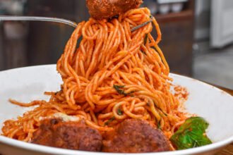 Macarrão espaguete com almôndegas de carne ao molho de tomate com cogumelos e queijo ralado.