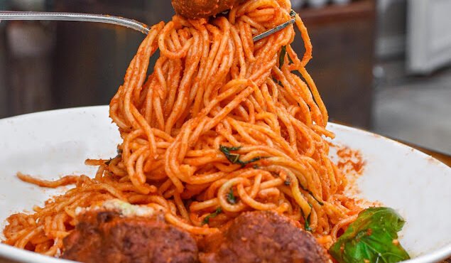 Macarrão espaguete com almôndegas de carne ao molho de tomate com cogumelos e queijo ralado.