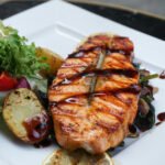 Filé de salmão assado no forno servido com batatas temperadas, limão e ervas frescas.