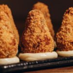 Coxinhas cremosas de frango sem massa tradicional, empanadas e douradas, servidas como petisco.