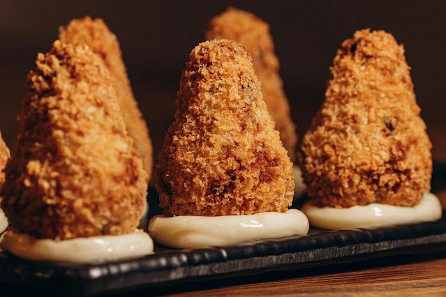 Coxinhas cremosas de frango sem massa tradicional, empanadas e douradas, servidas como petisco.