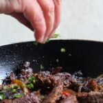 Carne bovina em tiras com cebola e pimentão preparada na frigideira.