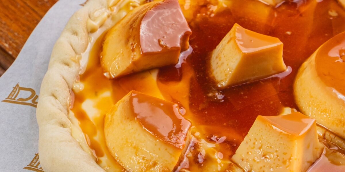 Pizza de pudim de leite condensado com pedaços de pudim e calda de caramelo