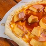 Pizza de pudim de leite condensado com pedaços de pudim e calda de caramelo
