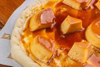 Pizza de pudim de leite condensado com pedaços de pudim e calda de caramelo
