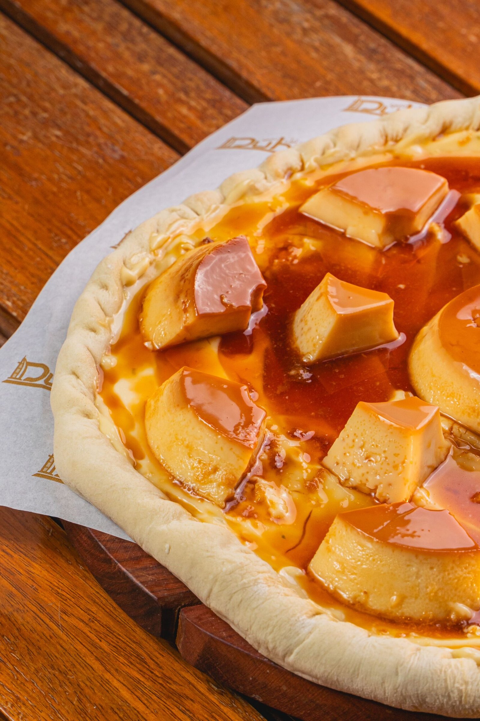 Pizza de pudim de leite condensado com pedaços de pudim e calda de caramelo