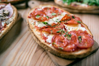 Mini pizzas feitas com pão francês, cobertas com molho de tomate, queijo derretido e ingredientes variados.